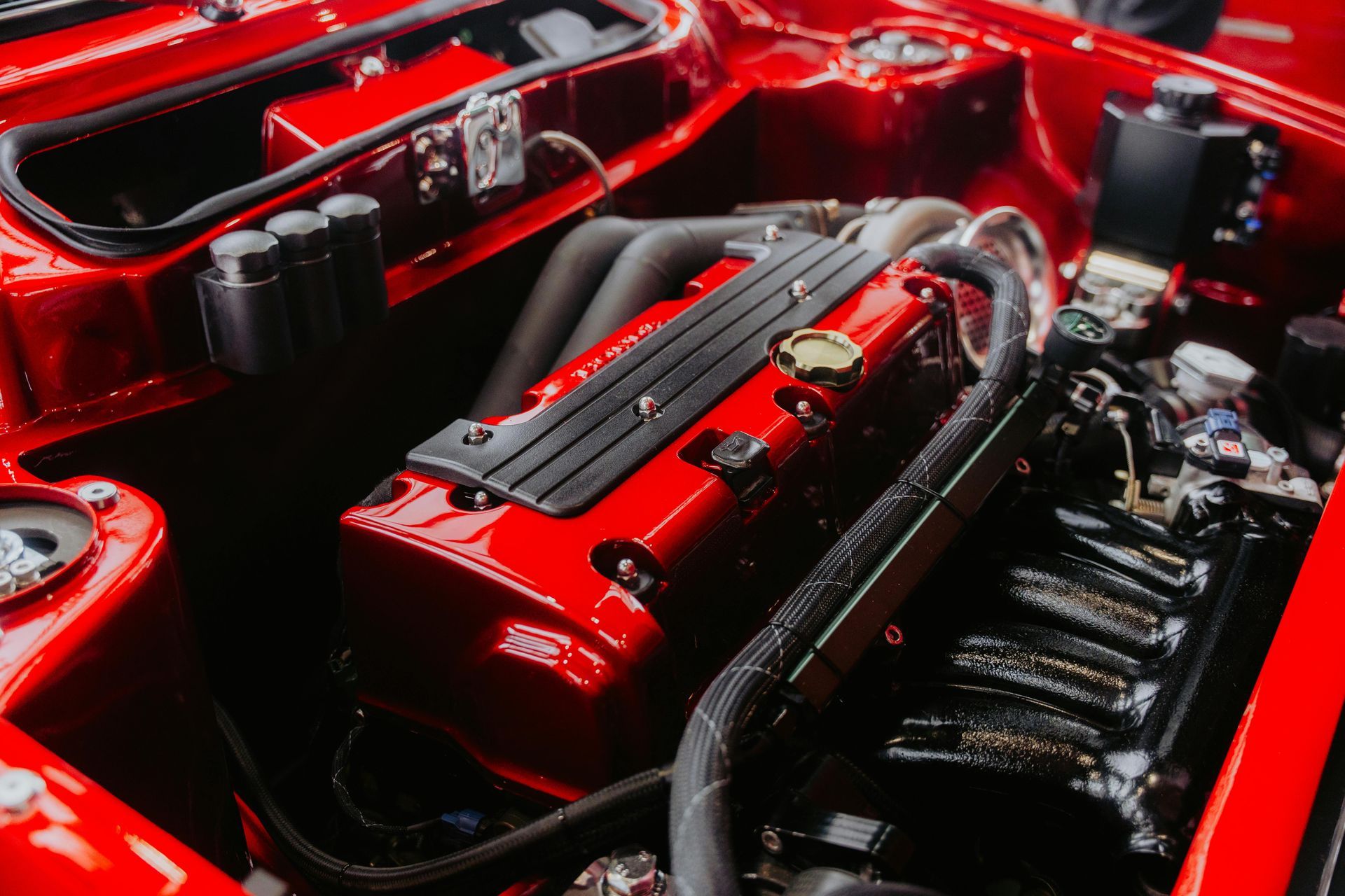 Red engine bay with a red engine block, black intake manifold, and various black components.