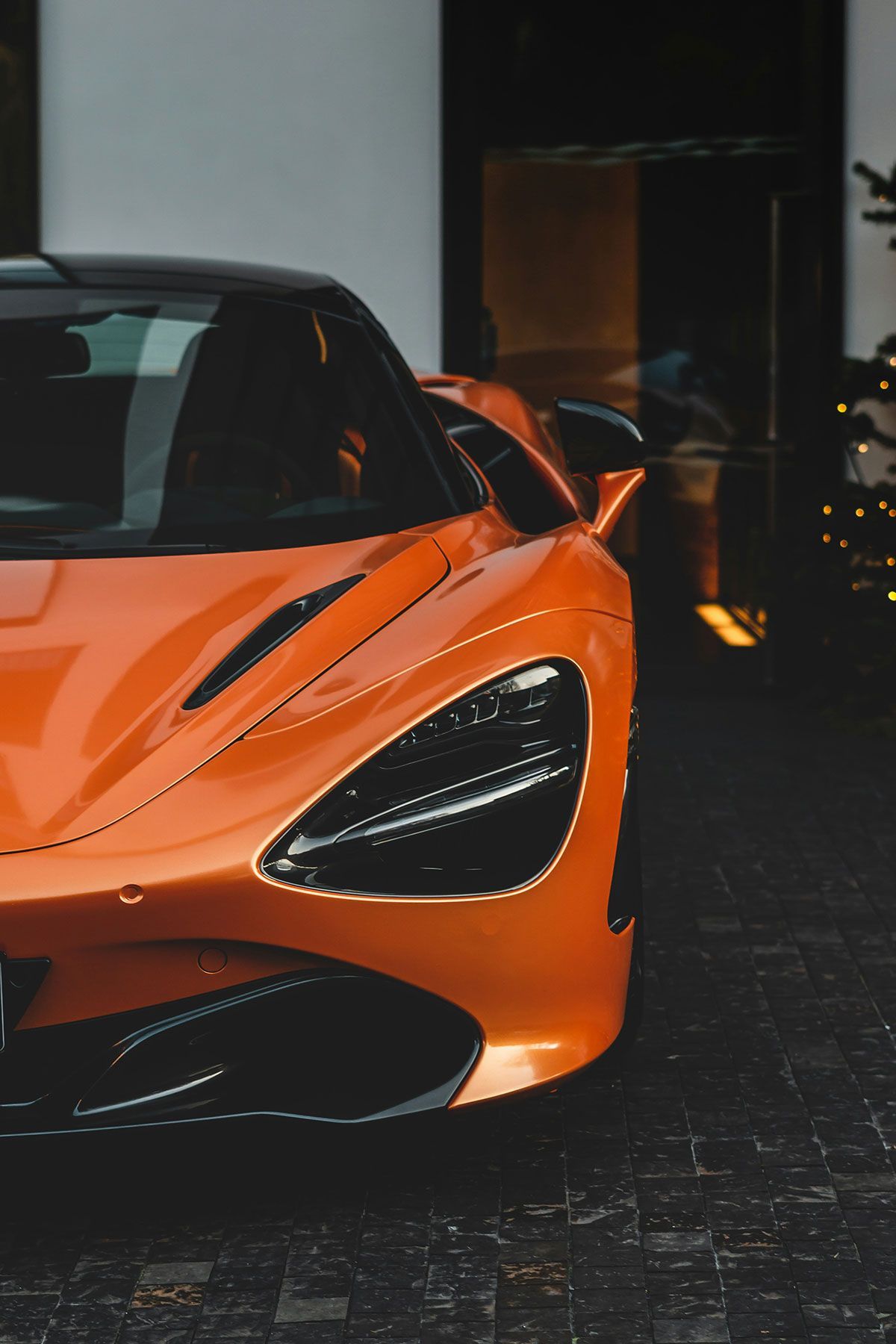 Orange McLaren sports car parked outside building, head-on view.